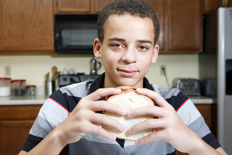 Teenage boy eating a sandwich