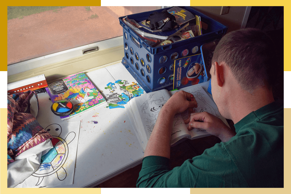 A male Pueblo Regional Center resident colors in a coloring book