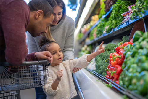 Parents and child shopping for produce at grocery store