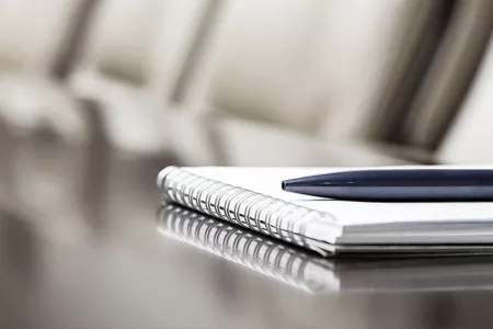 Stock photograph of notebook and pen on boardroom table