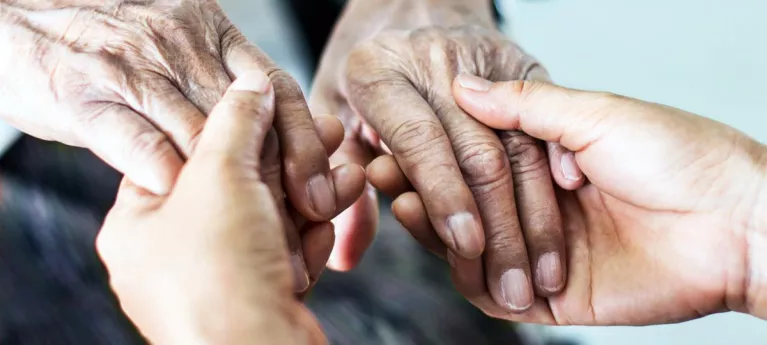 Photograph of someone holding the hands of an older person