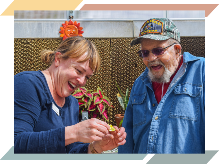 A woman showing an elderly veteran a flower