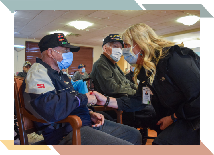 Image of a masked nurse and veterans resident holding hands