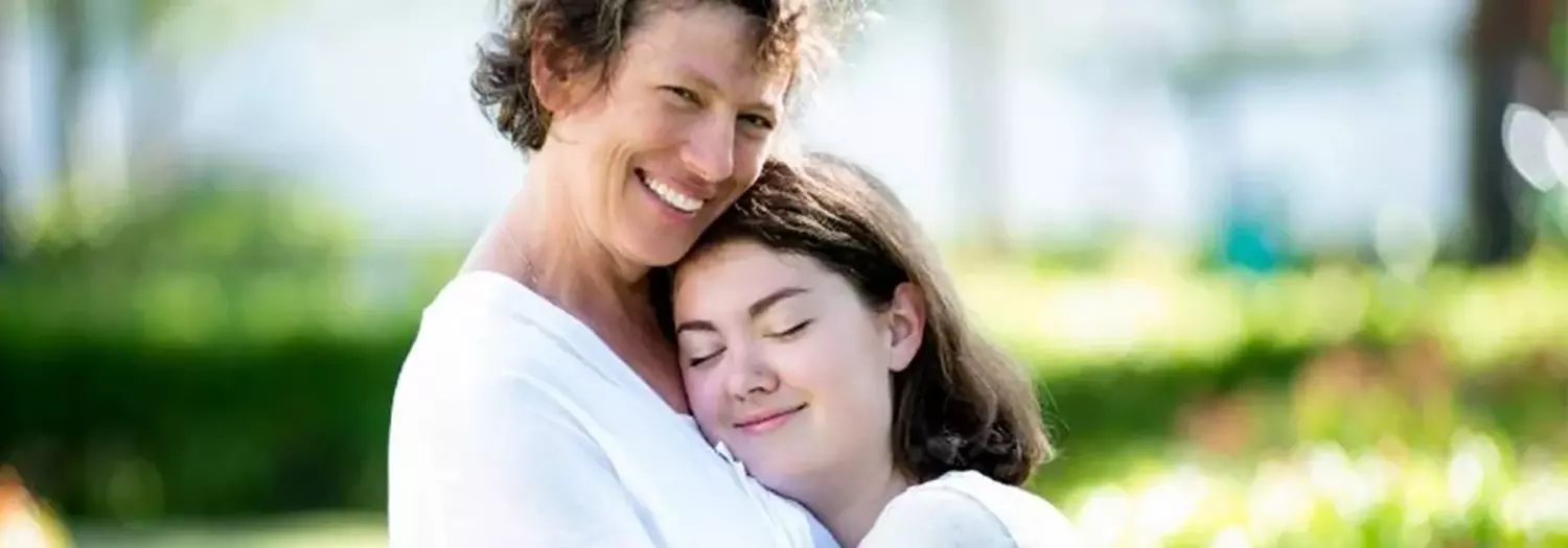 Photograph of a woman hugging a younger woman