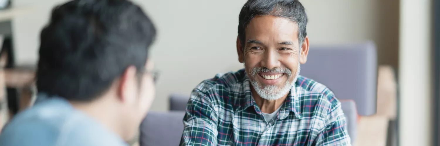 Smiling older man talking to another man