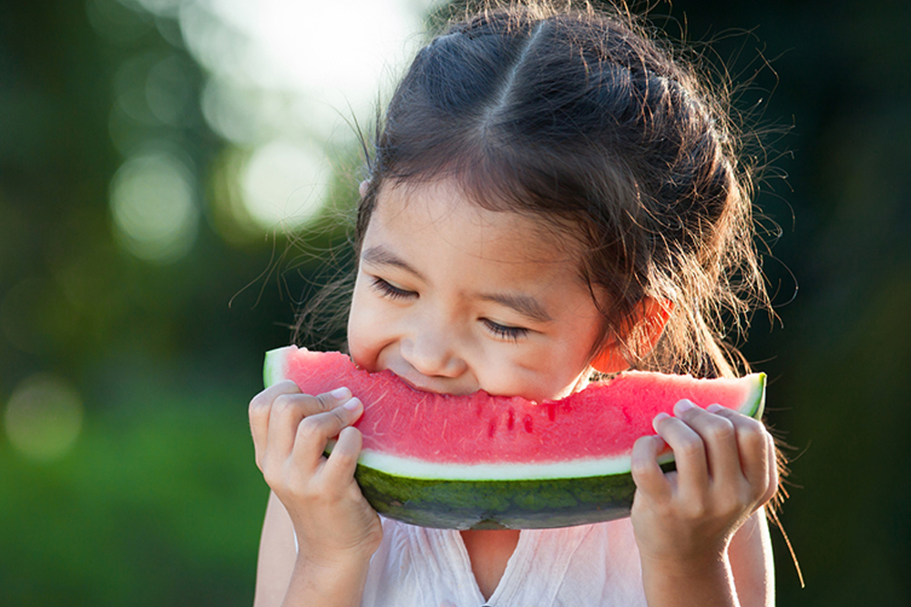 Young girl eating slice of watermelon